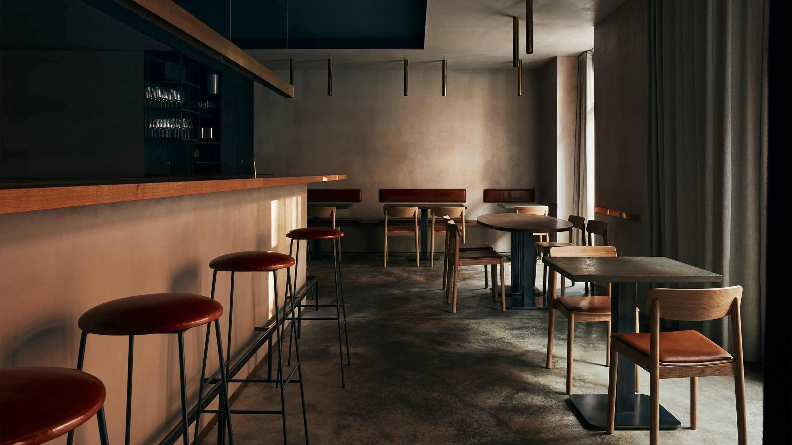 ein Gastraum mit mehreren Tischen und Stühlen und einem langen Bartresen