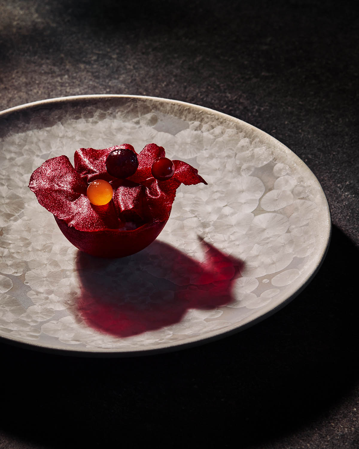  eine halbrundes rotes Kugelgericht mit kleinen Dekokügelchen liegt auf hellem Teller